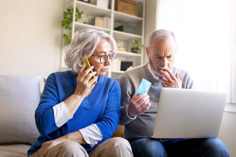 Oudere vrouw en man worstelen met online bankieren via laptop en telefoon, maar zijn op hun hoede voor phishing